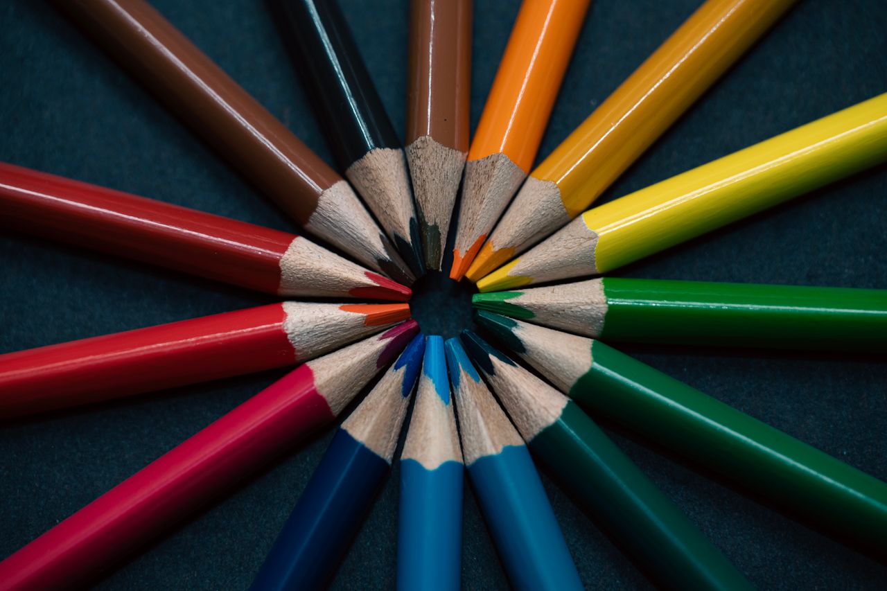services-bg A vivid display of multicolored pencils arranged in a circular pattern on a dark background.