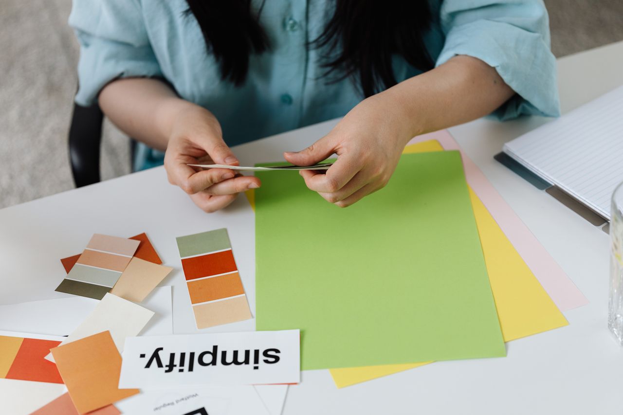 get-in-touch Person arranging colorful paper samples and swatches at a desk, fostering creativity and design.